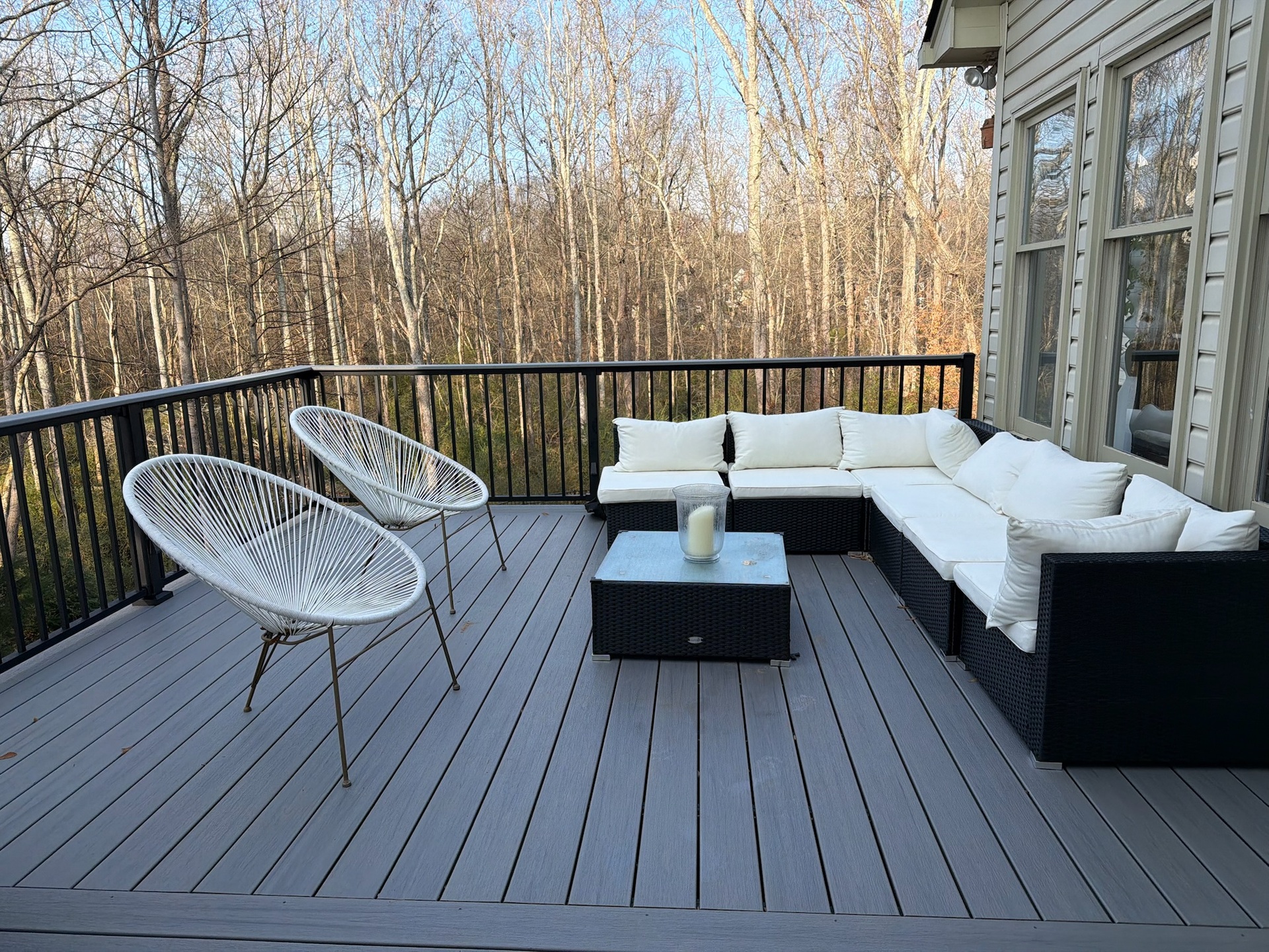 Modern outdoor deck featuring Trex Select Millstone flooring with stylish Trex Signature aluminum railing and a convenient cocktail railing, complemented by comfortable white seating and serene natural views.